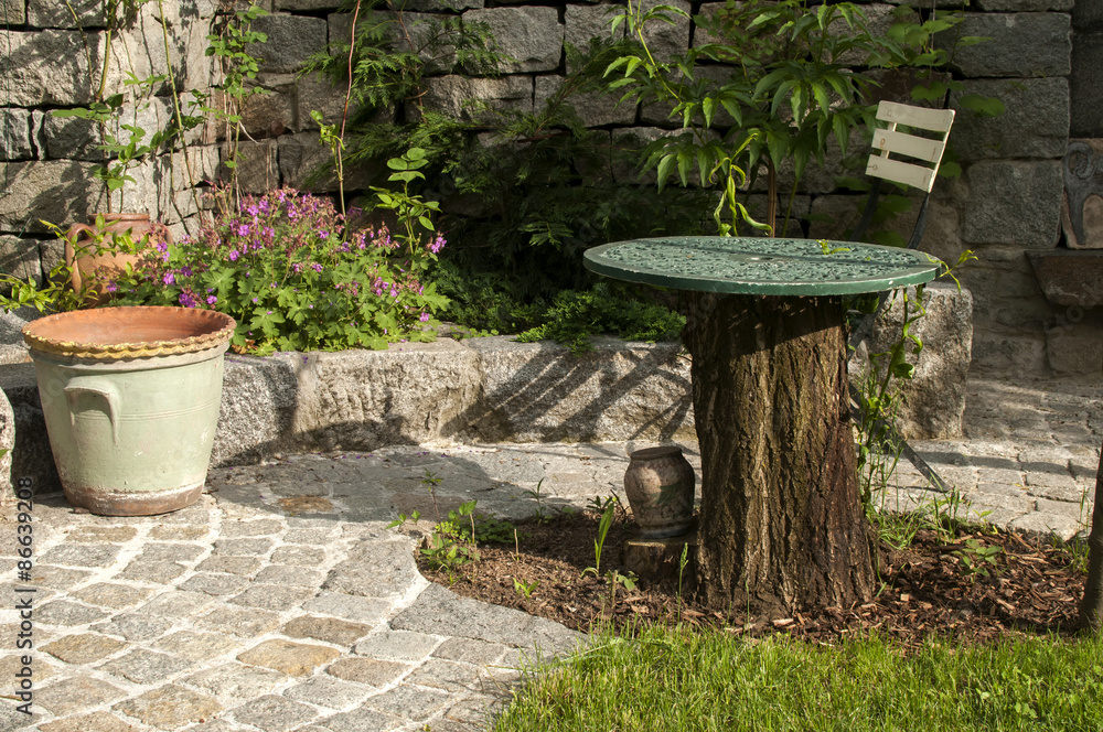 Detail of back yard garden with table, chair and pavement Detail of back yard garden with table, chair and pavement