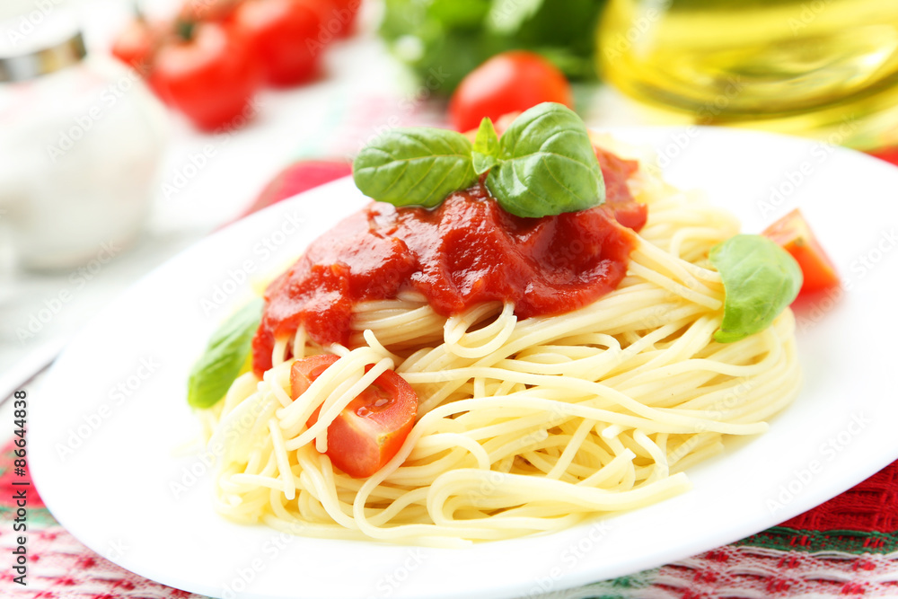 Spaghetti with tomatoes and basil on plate on white wooden backg Spaghetti with tomatoes and basil on plate on white wooden backg