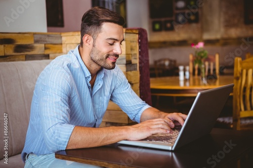 Smiling businessman using his laptop at the cafe