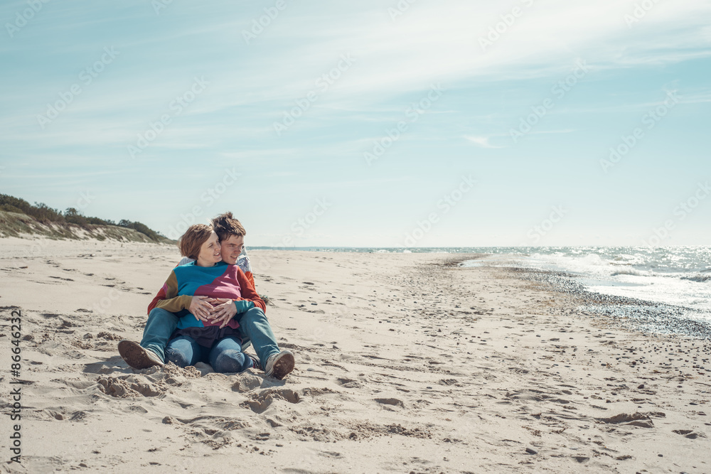 Young man embracing a woman sitting on the beach Young man embracing a woman sitting on the beach