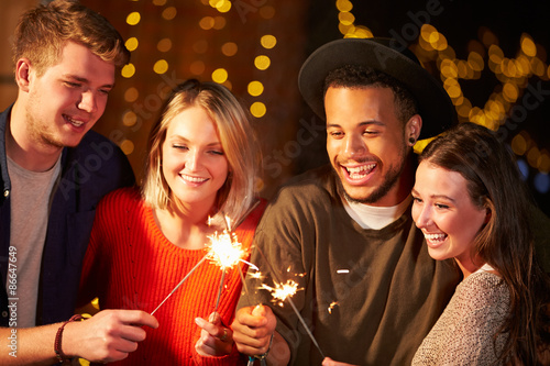 Group Of Friends Lighting Sparklers At Outdoor Party