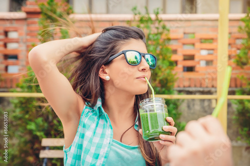 Принти на полотні Woman with sunglasses drinking green vegetable smoothie outdoors