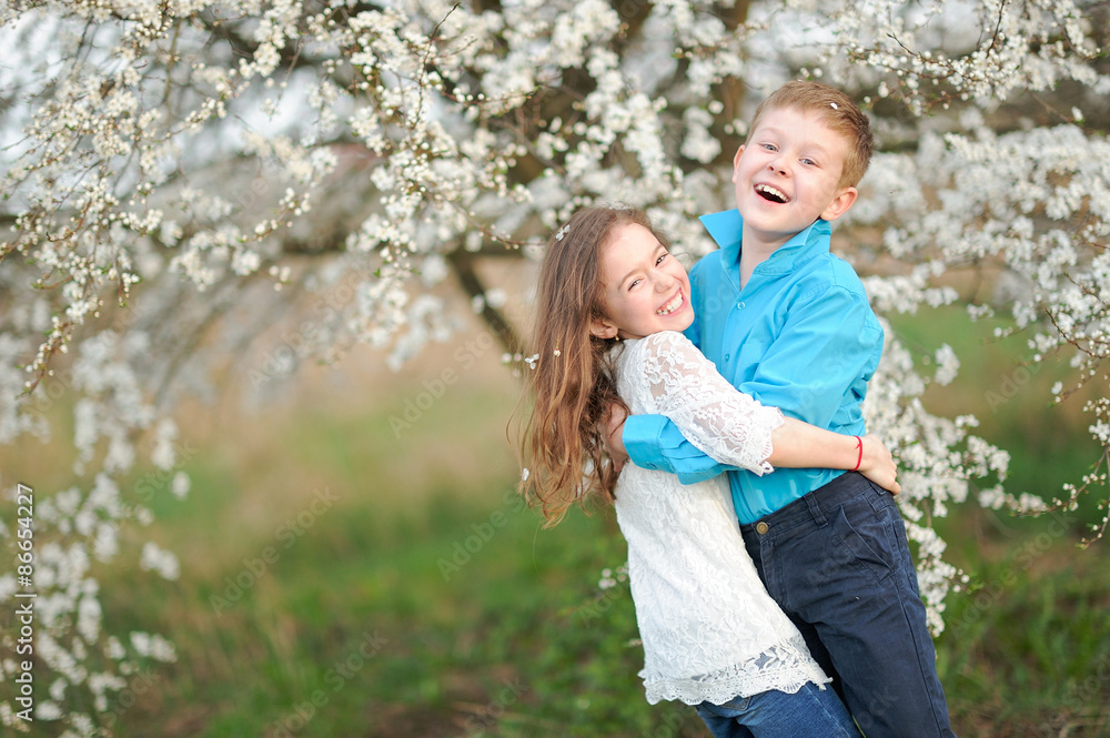 Fototapeta premium Portrait of a boy and girl in the lush garden