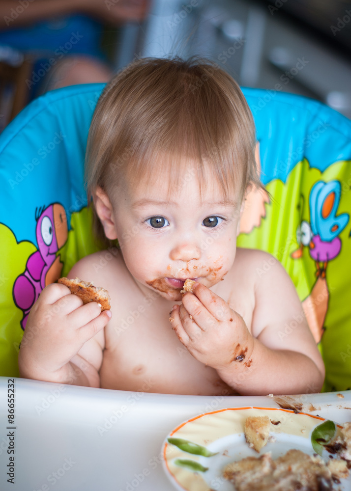 Child eats cake in the highchair Child eats cake in the highchair