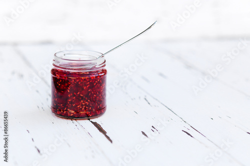 Raspberry jam in a jar on the wooden table
