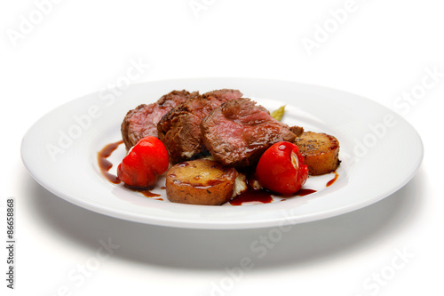 Raw steak with grilled potato and cherry tomato