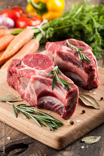 Raw beef meat on cutting board and fresh vegetables