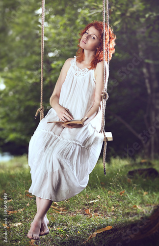 Beautiful red hair woman on a swing