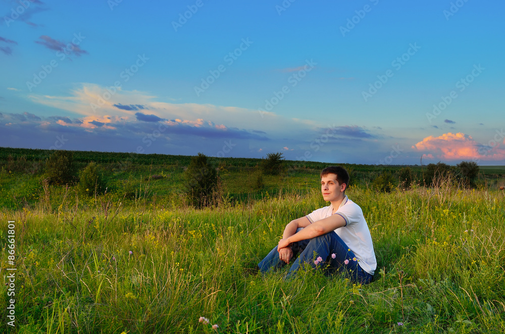 smiling young man on the hills with summer flowers