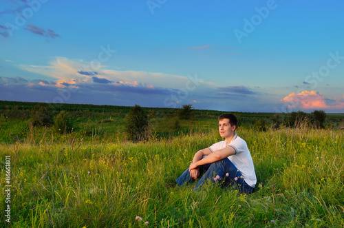 smiling young man on the hills with summer flowers