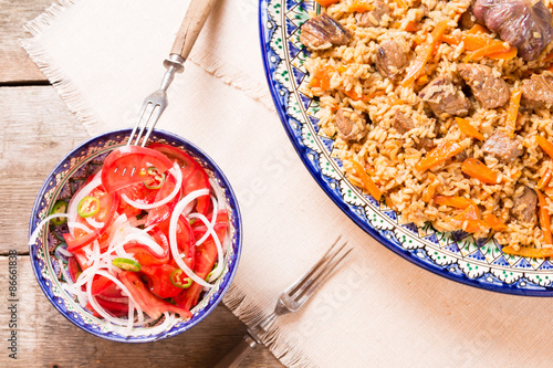 Pilaf and achichuk salad in handmade plate on wooden background photo