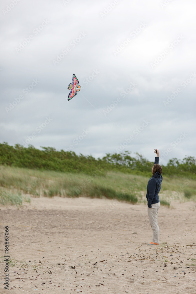 Man launching a kite in the sky, windy day at the beach