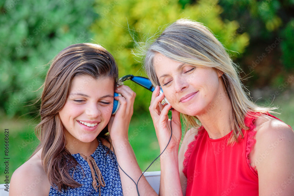 Ταπετσαρία Cute young girl with her mother listening music together with complicity