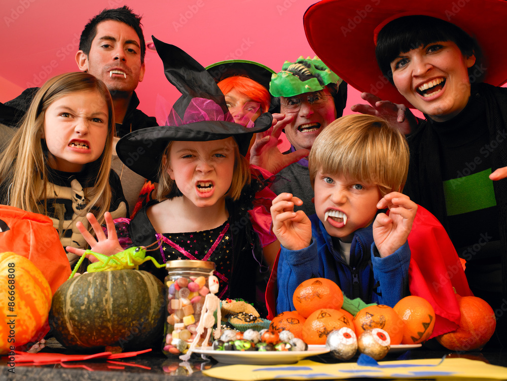 Family/friends posing for the camera in their halloween costumes. They are standing in the kitchen with party food and treats set out in front of them. Family/friends posing for the camera in their halloween costumes. They are standing in the kitchen with party food and treats set out in front of them.