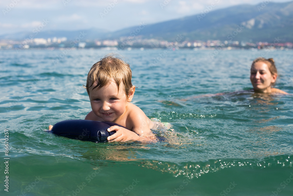 Little boy with his mother swims in the sea