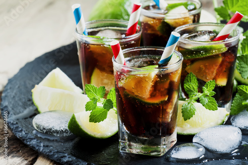 Cuba Libre with lime, mint and ice in a glass, selective focus