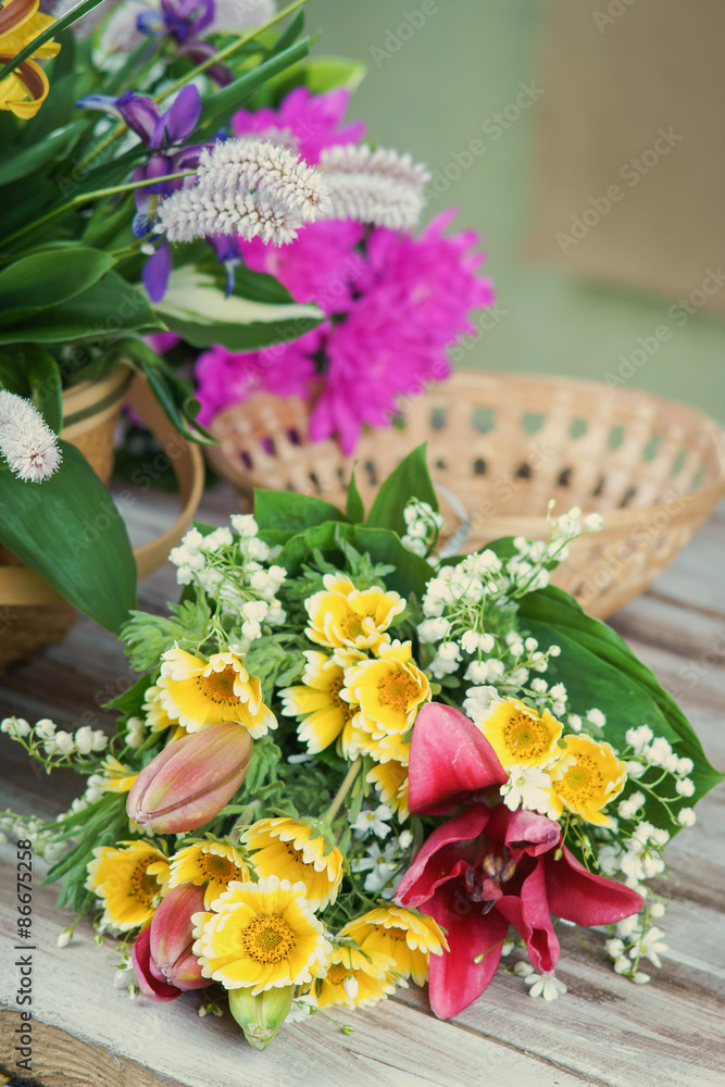 Bunch of summer flowers on the table and wicker basket Bunch of summer flowers on the table and wicker basket