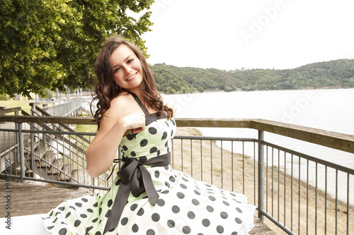 lächelnde Frau in grünem Petticoat Kleid mit anliegender Hand photo