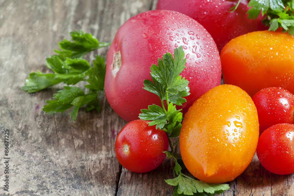 Assorted tomatoes: orange, pink, red cherry tomatoes with parsle Assorted tomatoes: orange, pink, red cherry tomatoes with parsle