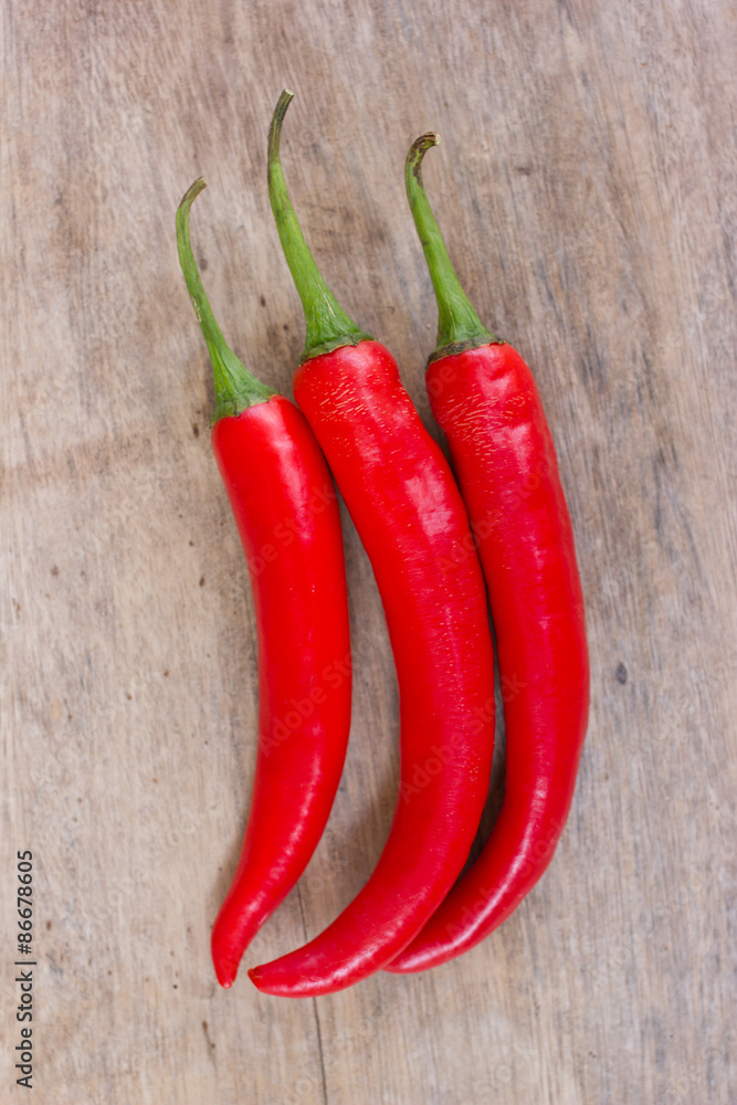 Hot red chili or chilli peppers over wooden background
