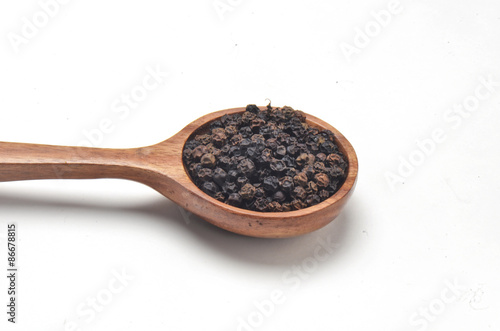 Black pepper spices in wooden spoon