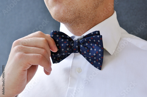 Man's hands touches bow-tie