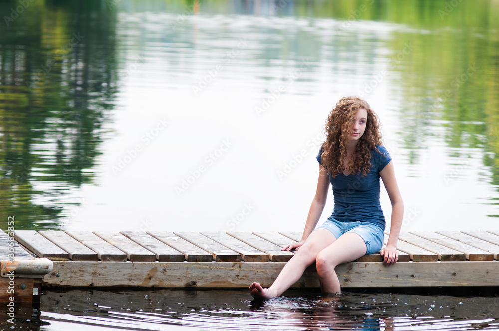 teen girl sitting on a dock with her legs in the water Stock Photo ...