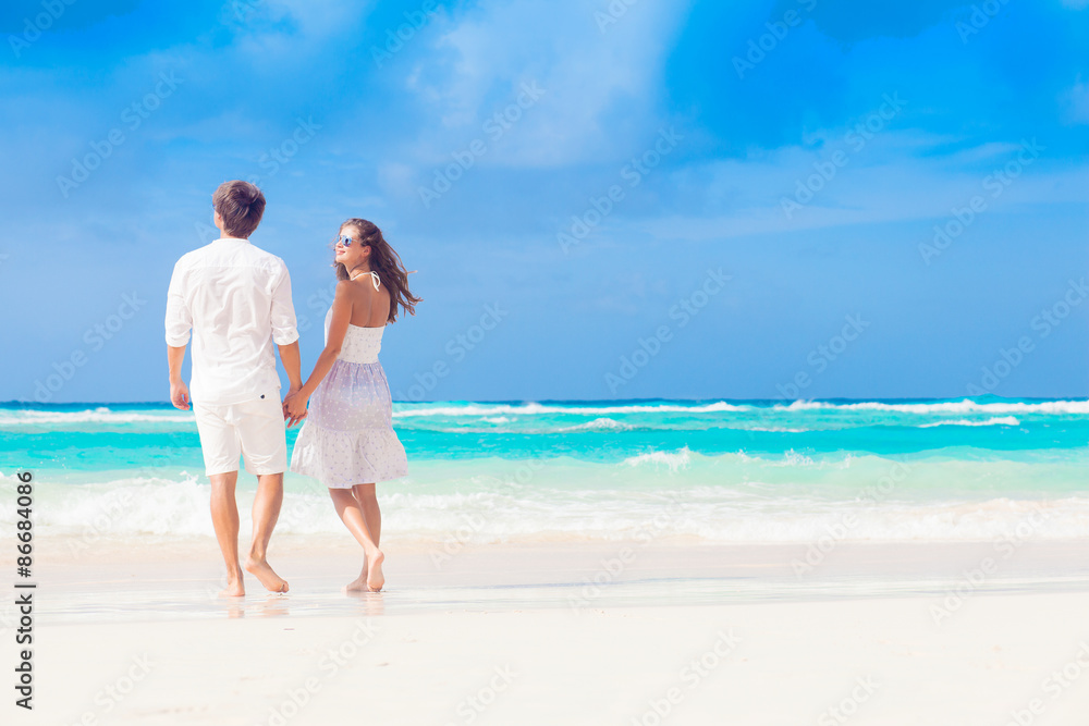 back view of happy romantic young couple walking at the beach