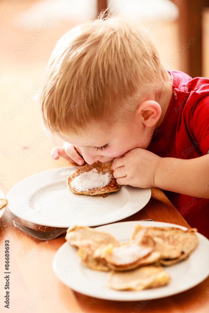 Little boy eating apple pancakes at home