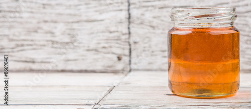 Obraz na plátně Honey in a mason jar over rustic weathered wooden background