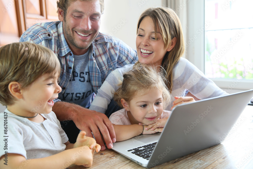 Parents with kids at home using laptop computer Parents with kids at home using laptop computer