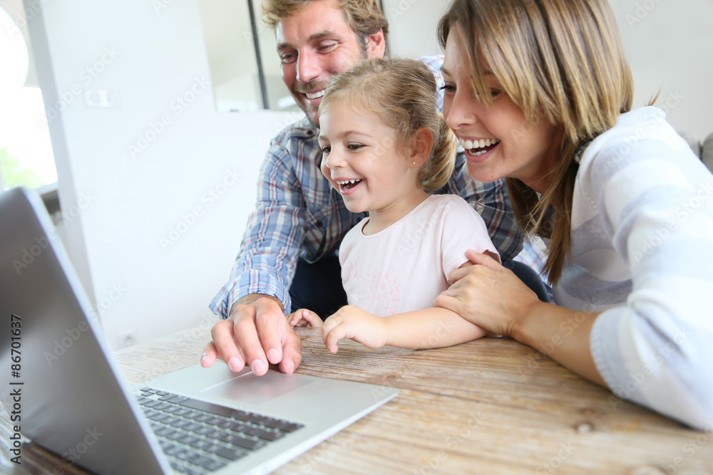 Parents with little girl laughing in front of laptop computer Parents with little girl laughing in front of laptop computer