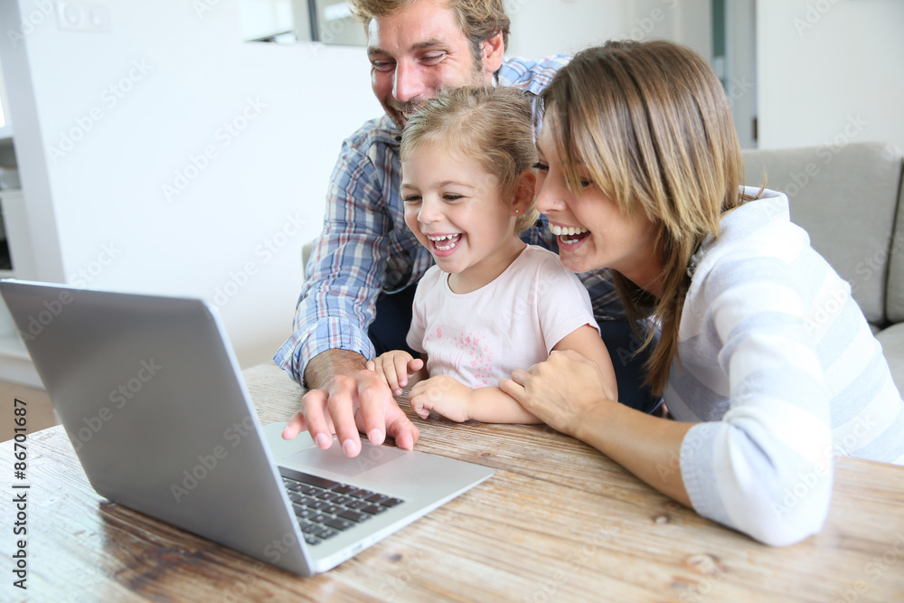 Parents with little girl laughing in front of laptop computer Parents with little girl laughing in front of laptop computer