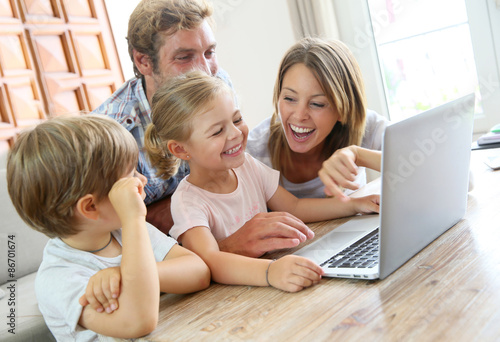 Parents with kids at home using laptop computer