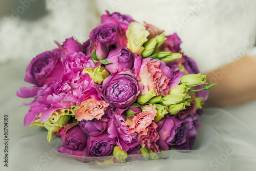 bride in white dress holding bouquet of roses