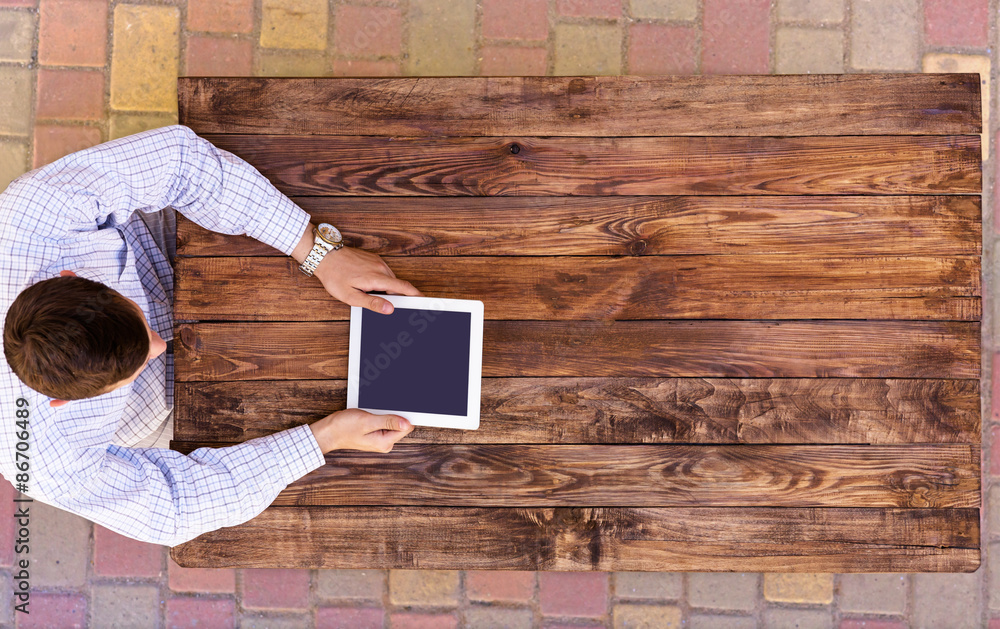From above image man browsing gadget at empty wood desk. Natural wood ...