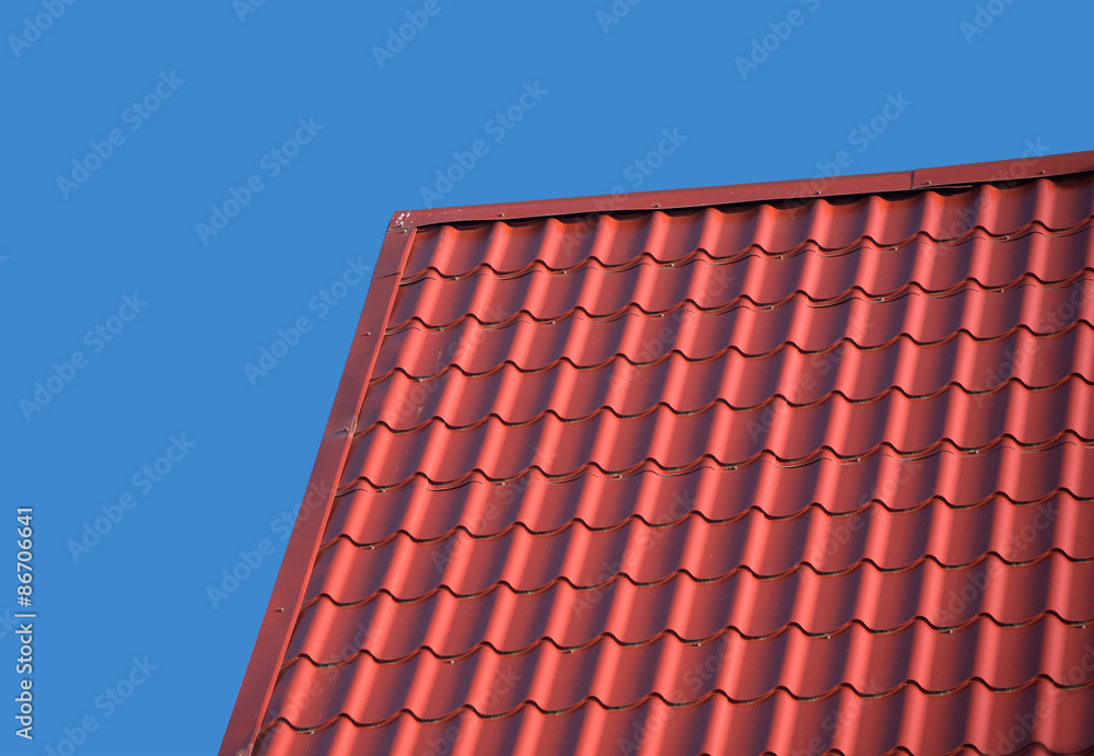 Fototapeta premium Top of country house roof covered with metal tile isolated on blue closeup