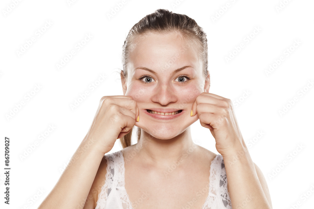Smiling young blonde pulls out her cheeks with her fingers Smiling young blonde pulls out her cheeks with her fingers