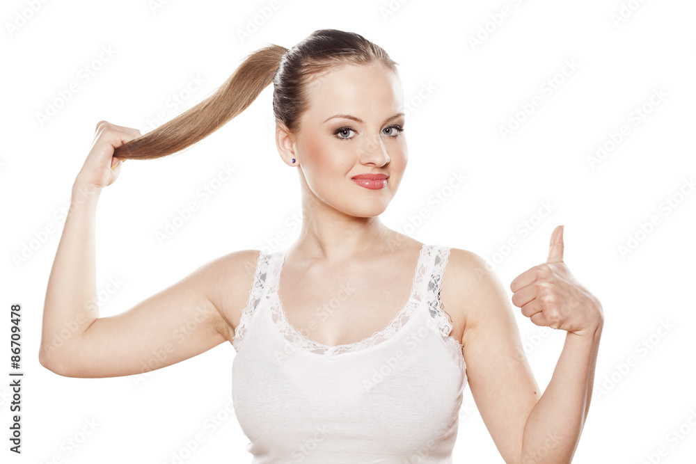 young happy woman holding her ponytail and showing thumbs up young happy woman holding her ponytail and showing thumbs up