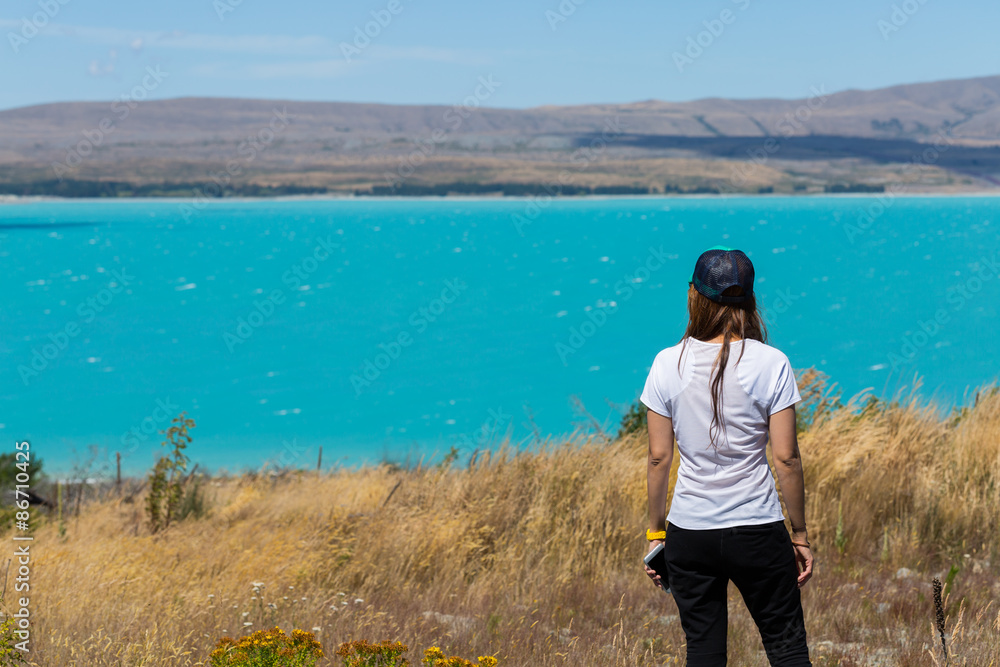 back view of woman standing and looking out towards turquoise la