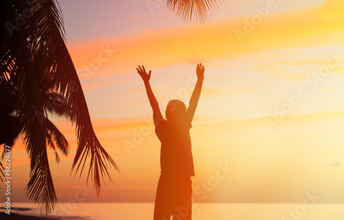 silhouette of man with his hands up at sunset