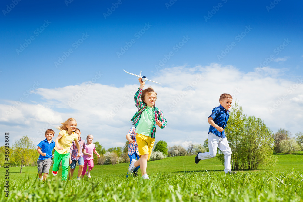 Running boy with airplane toy and other children Running boy with airplane toy and other children