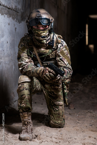 Armed man with mask and gun  standing on his knee