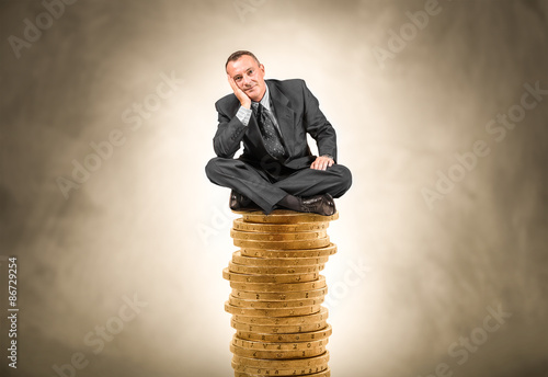 uomo d'affari seduto sopra un pila di moneta gigante photo