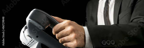 Closeup of businessman picking up  a black landline telephone re