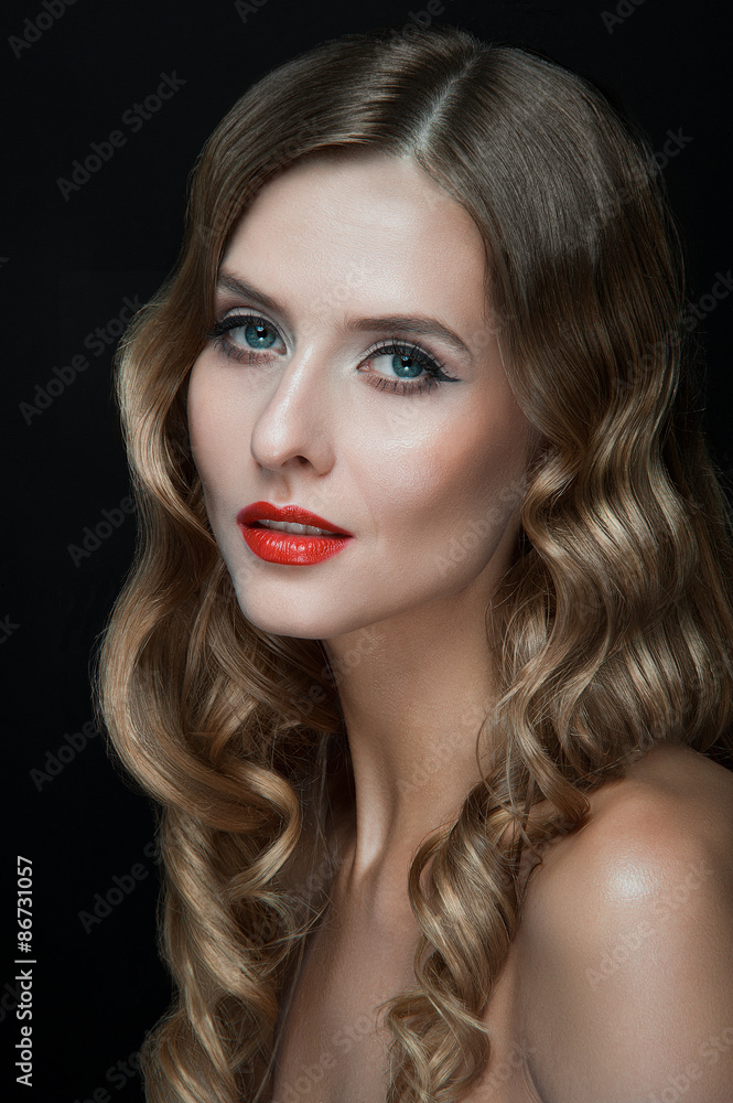 Fototapeta premium Portrait of beautiful young women with red lips, wavy hair, black eyeliner. Beauty. Studio shot. Black background.