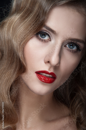 Portrait of beautiful young women with red lips  wavy hair  black eyeliner. Beauty. Studio shot. Black background.
