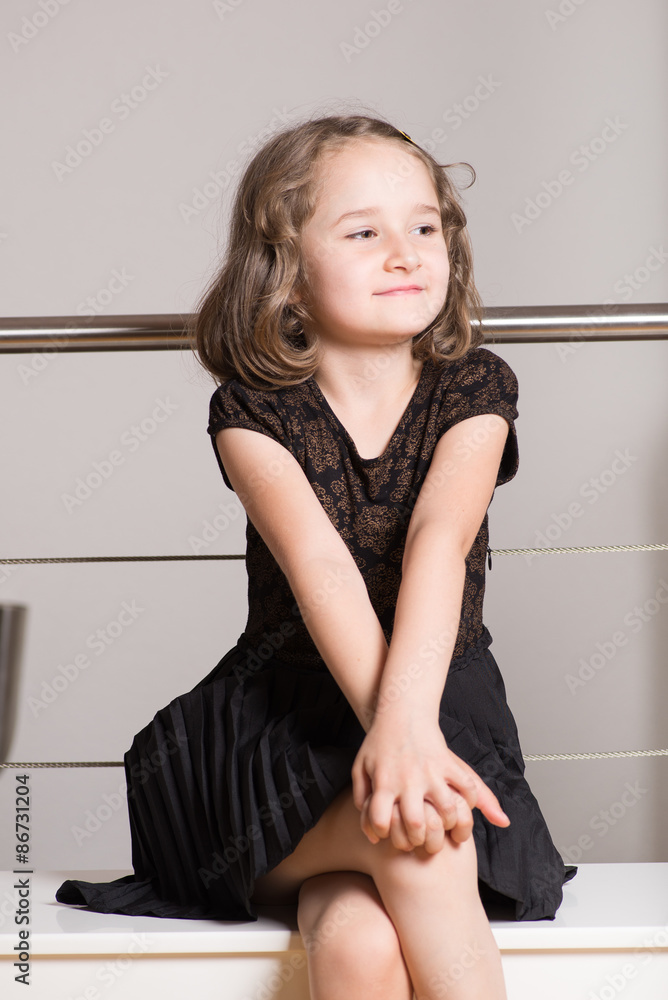 Cute little blonde girl posing on a bench 