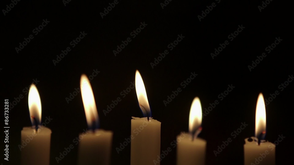 Rack focus on lit candles against black background. Flames are being blown due to wind in studio.
Rack focus on lit candles against black background. Flames are being blown due to wind in studio.