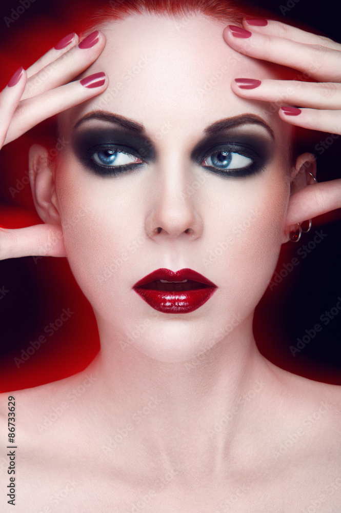 Beauty portrait of young women with blue eyes, red lipstick, smoky eyes, hand touching face on black background. Beauty portrait of young women with blue eyes, red lipstick, smoky eyes, hand touching face on black background.